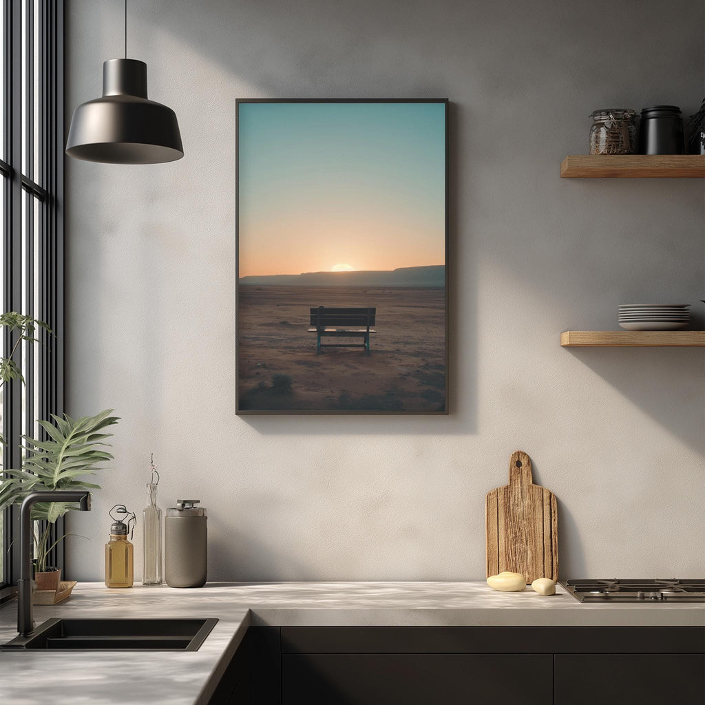 a serene scene of a bench in a desert landscape, with a warm sunset in the background. The bench is positioned in the middle of the frame, and the warm hues of the setting sun create a peaceful atmosphere. The kitchen counter in the foreground is adorned with various kitchen items, including a cutting board, a bottle, and a vase, adding a touch of everyday life to the tranquil desert scene.