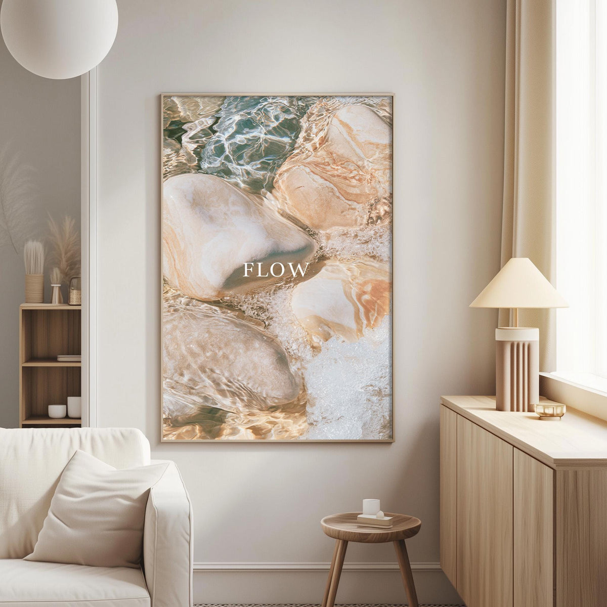 a living room with a large framed print hanging on the wall, depicting a beach scene with rocks and water. The print has the word "FLOW" written on it.