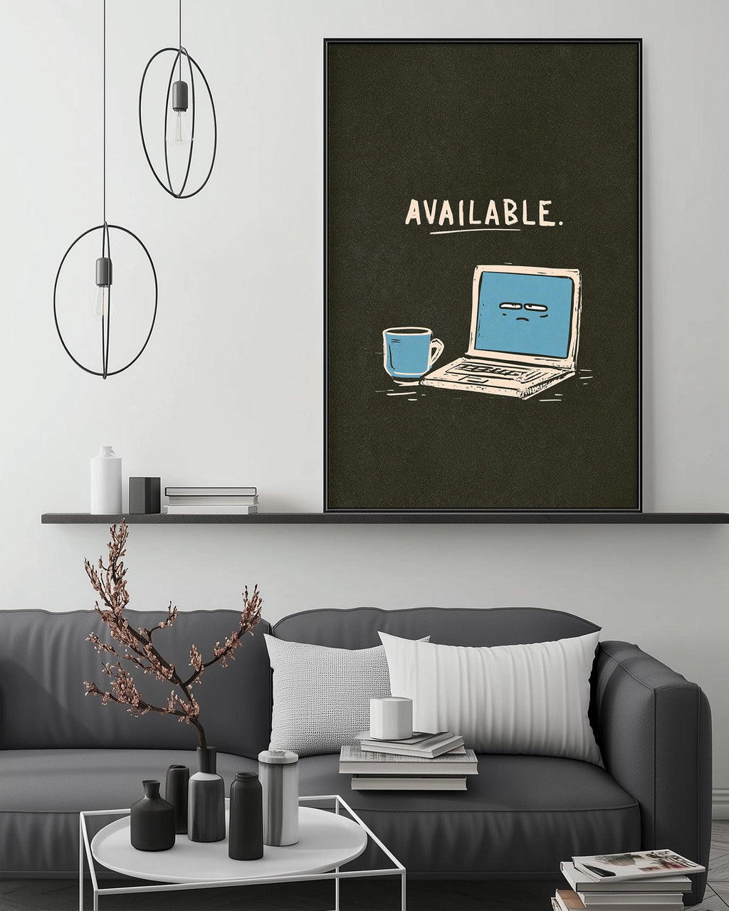 a living room with a gray couch, a coffee table, and a large framed poster on the wall. The poster depicts a laptop and a coffee cup, with the word "AVAILABLE" written above them.