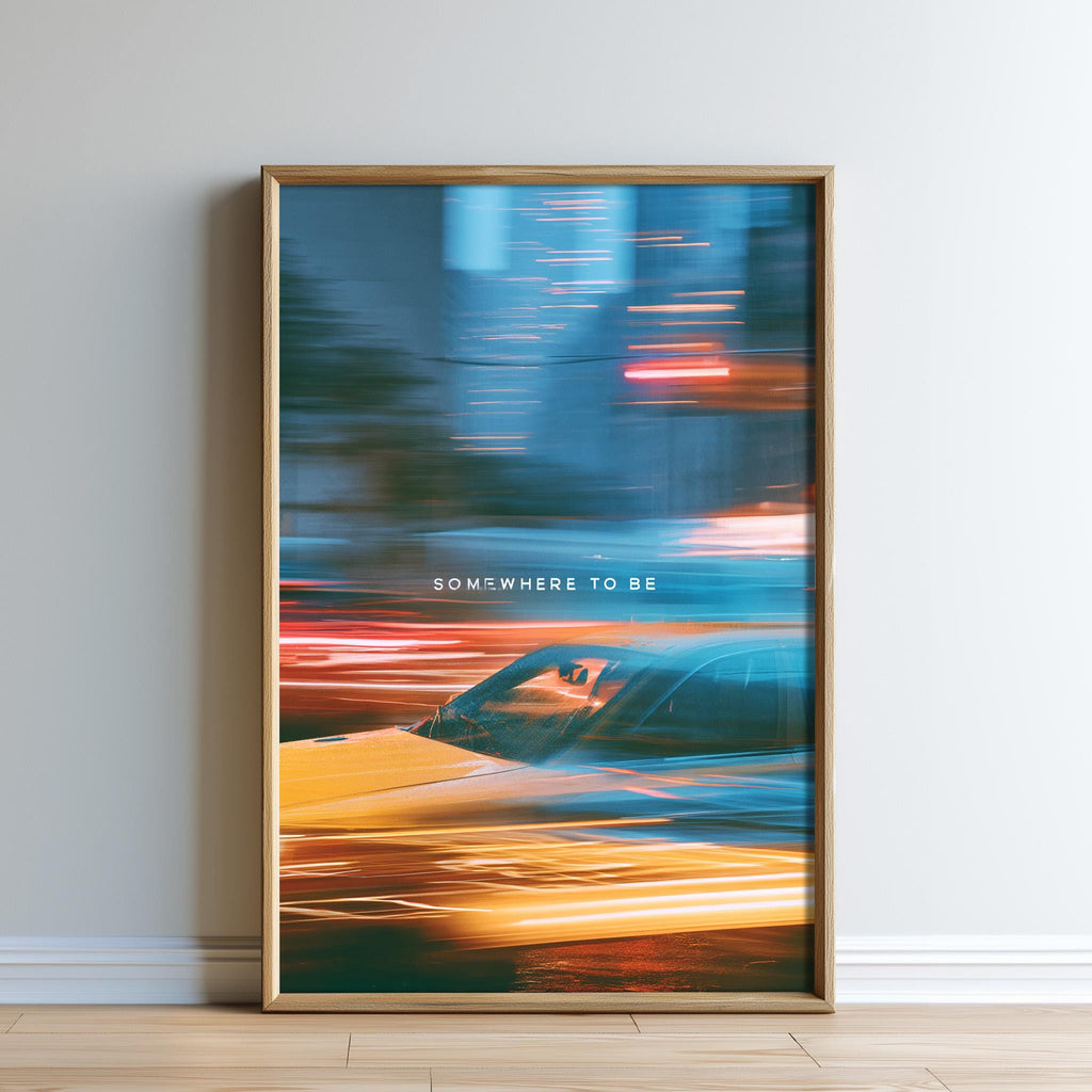 The image is a framed poster with a blurred car in motion, creating a sense of movement and speed. The text "SOMEWHERE TO BE" is displayed in the bottom right corner of the poster.