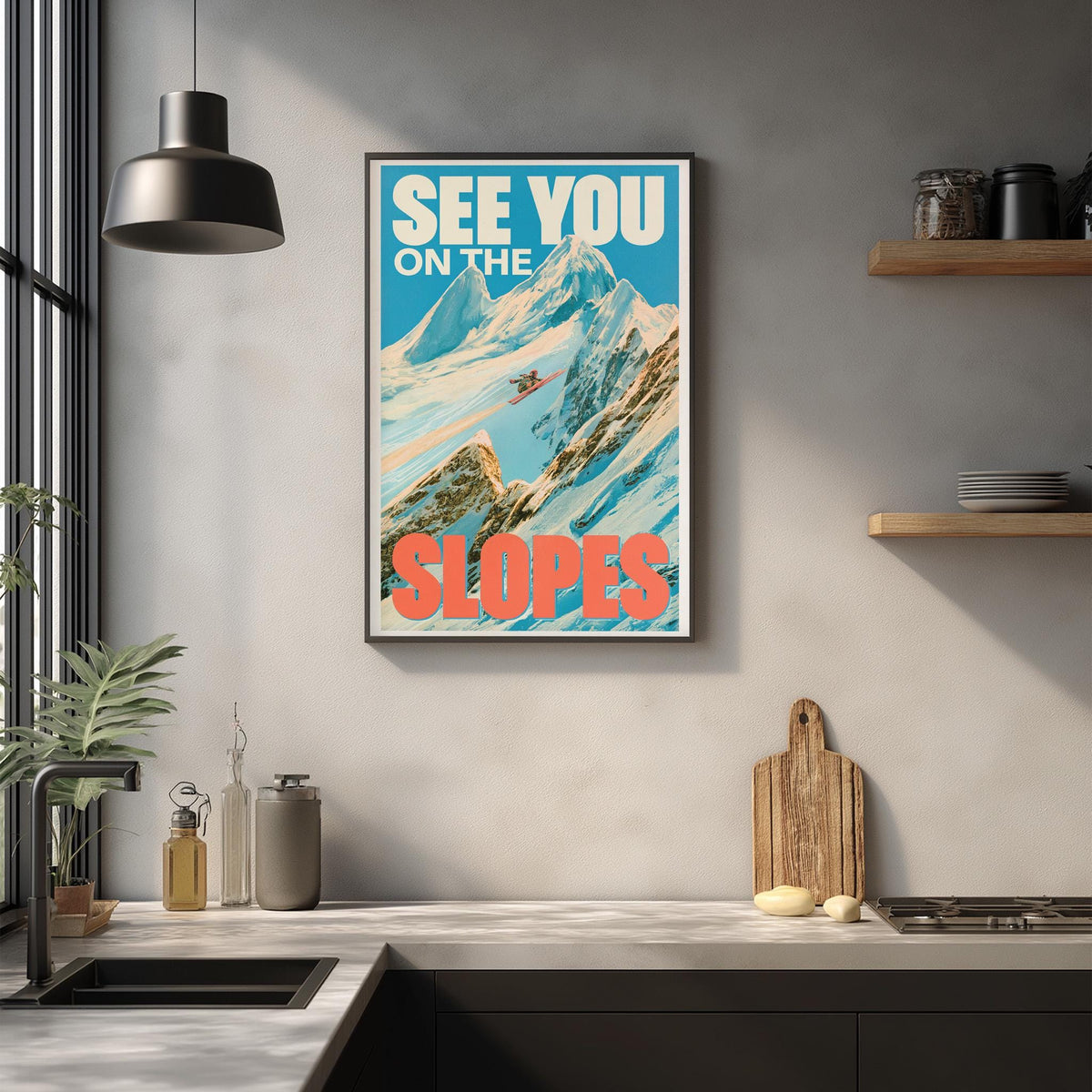 a framed poster of a mountain landscape with the text "See You on the Slopes" hanging on a wall above a kitchen counter.