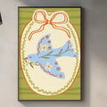 a kitchen counter with various kitchen items, including a cutting board, a soap dispenser, and a potted plant. Above the counter, there is a framed illustration of a bird with a bow around its neck, which appears to be a decorative piece on the wall.