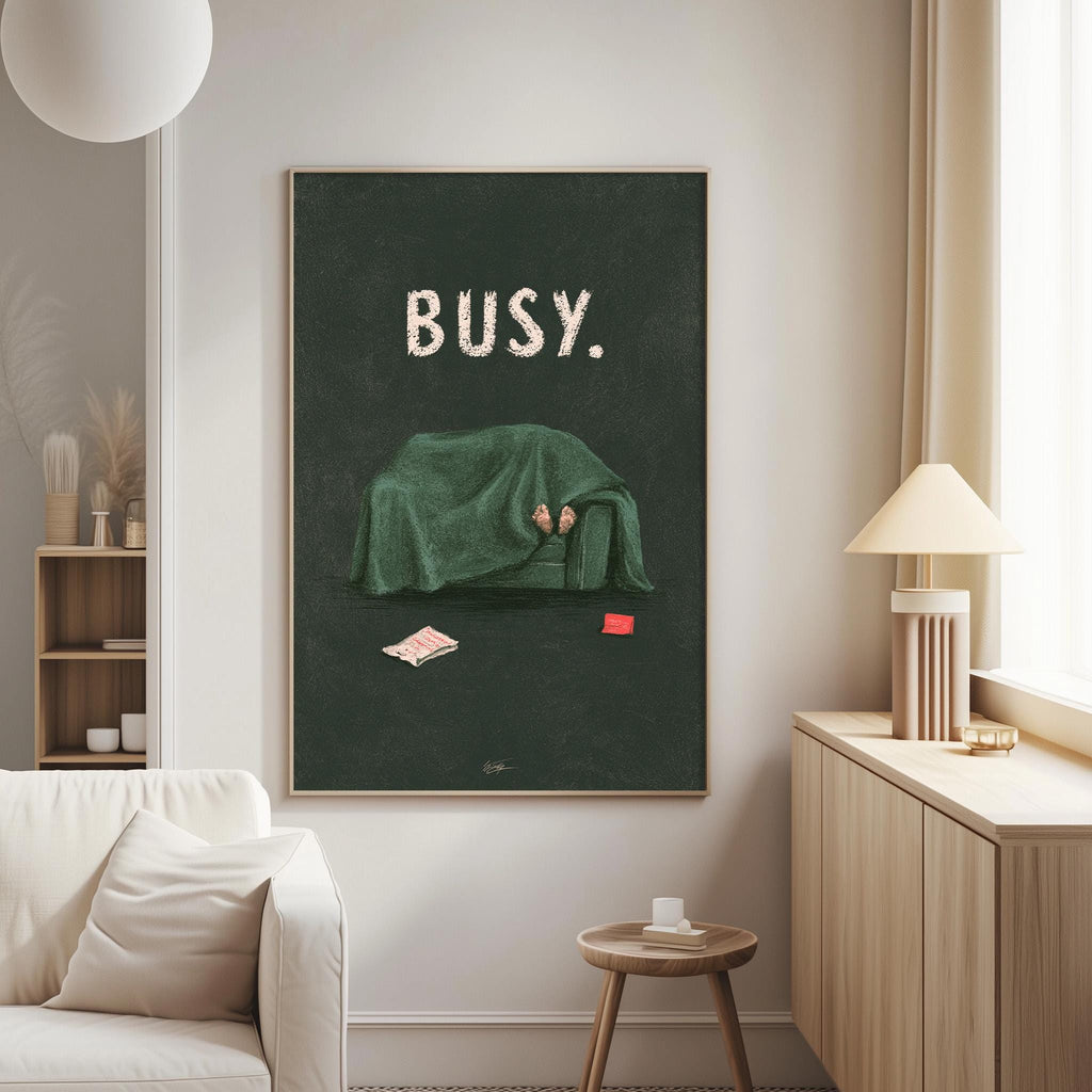 a cozy living room with a large framed poster of a person under a green blanket, sitting on a couch with a book and a red object on the floor.