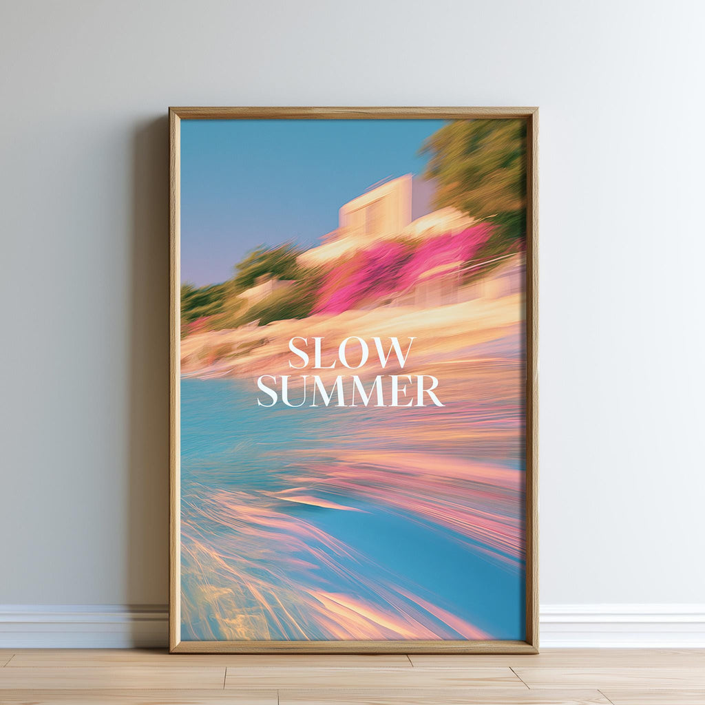 The image is a framed poster with a blurred, colorful background depicting a beach scene with a building and trees. The text "SLOW SUMMER" is prominently displayed in the center of the poster.