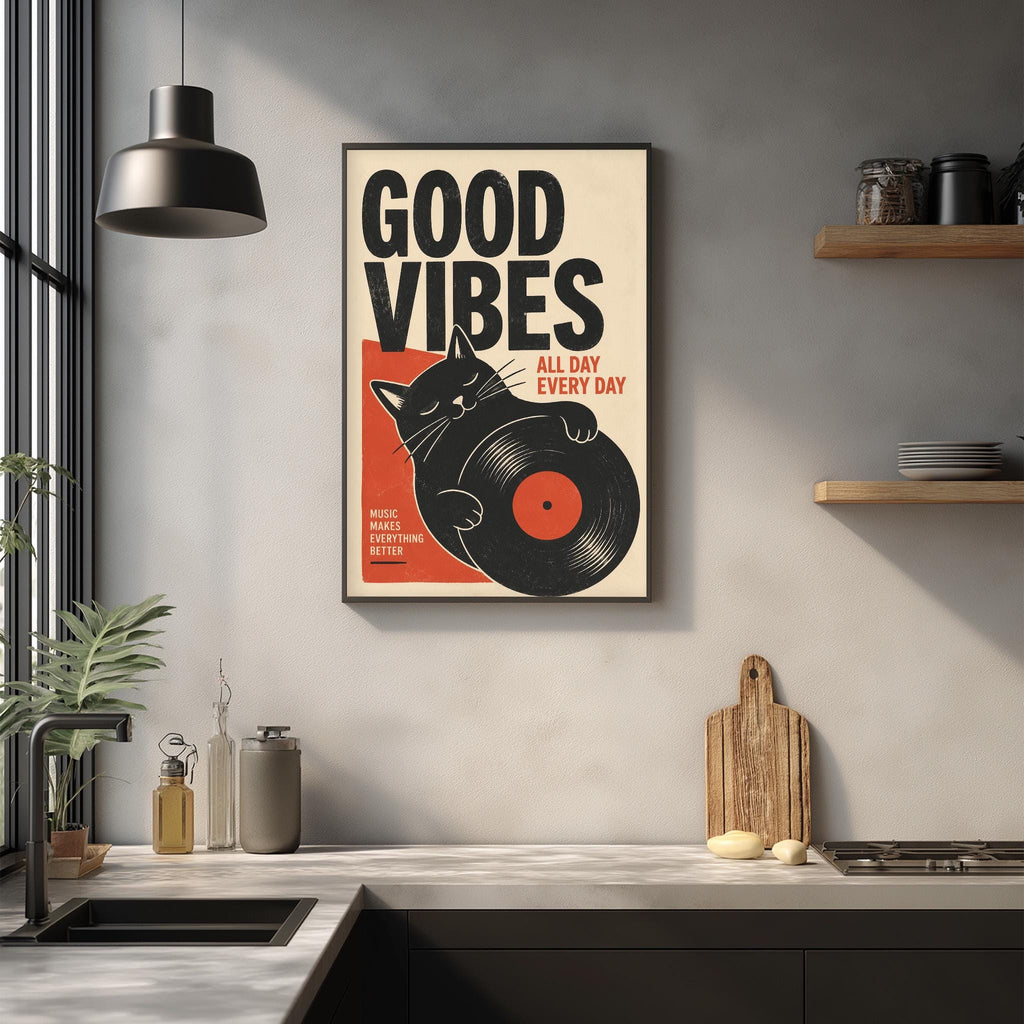 a framed poster with the text "GOOD VIBES ALL DAY EVERY DAY" and an illustration of a cat holding a vinyl record. The poster is displayed on a wall above a kitchen counter with various kitchen items such as a cutting board, a bottle, and a bowl.