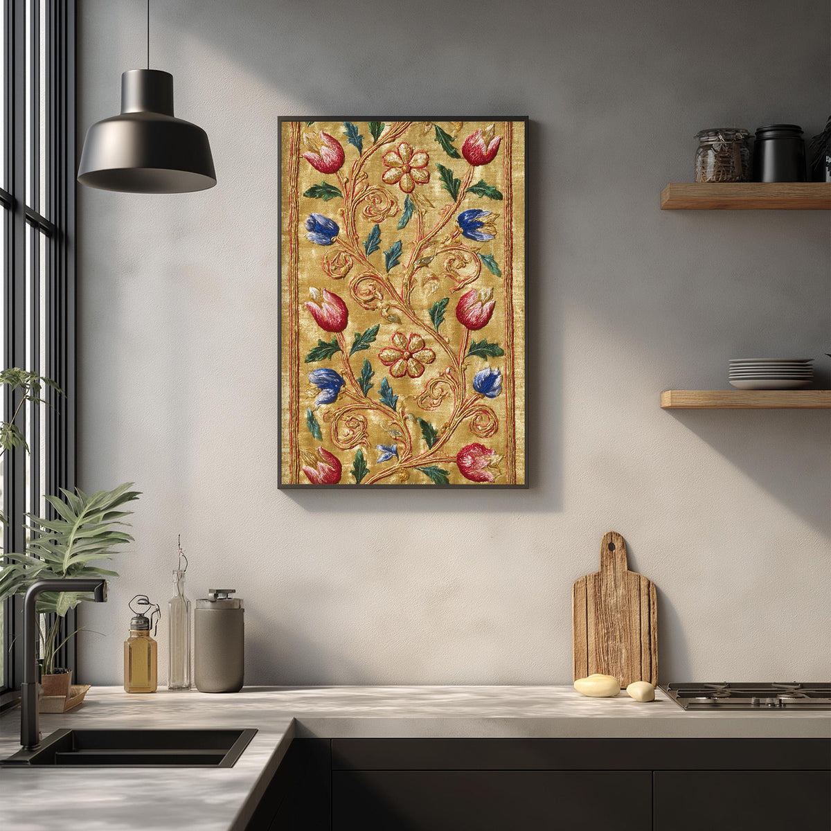 a kitchen counter with a framed floral tapestry hanging above it, a wooden cutting board, and various kitchen items such as a bottle, a canister, and a bowl.
