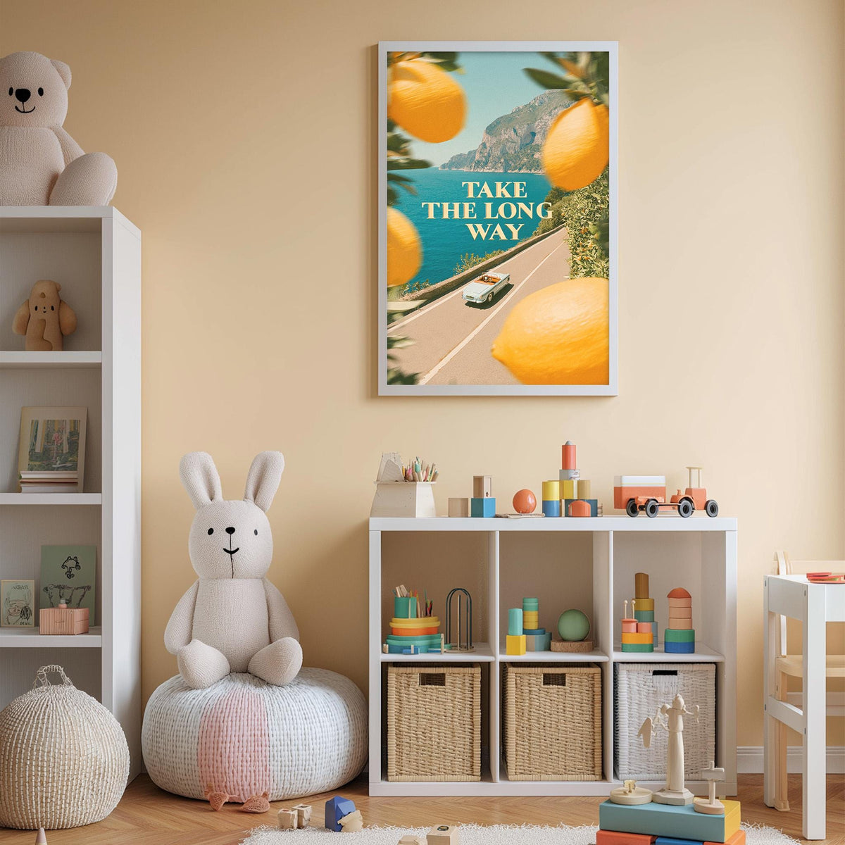 A child's bedroom with a white bookshelf, a stuffed rabbit, and a toy train set. Above the bookshelf is a framed poster with the text "TAKE THE LONG WAY" and an illustration of a road with a car and a scenic landscape.