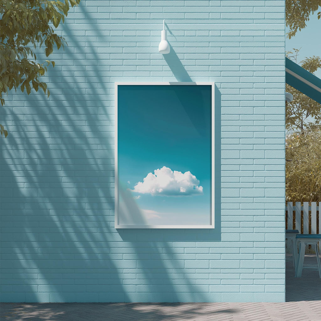a blue brick wall with a framed picture of a cloud hanging on it. The picture is set against a bright blue sky, creating a serene and calming atmosphere.