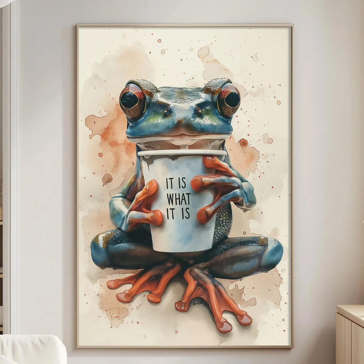a large painting of a frog sitting on a table and holding a cup, with the text "IT IS WHAT IT IS" written on the cup.