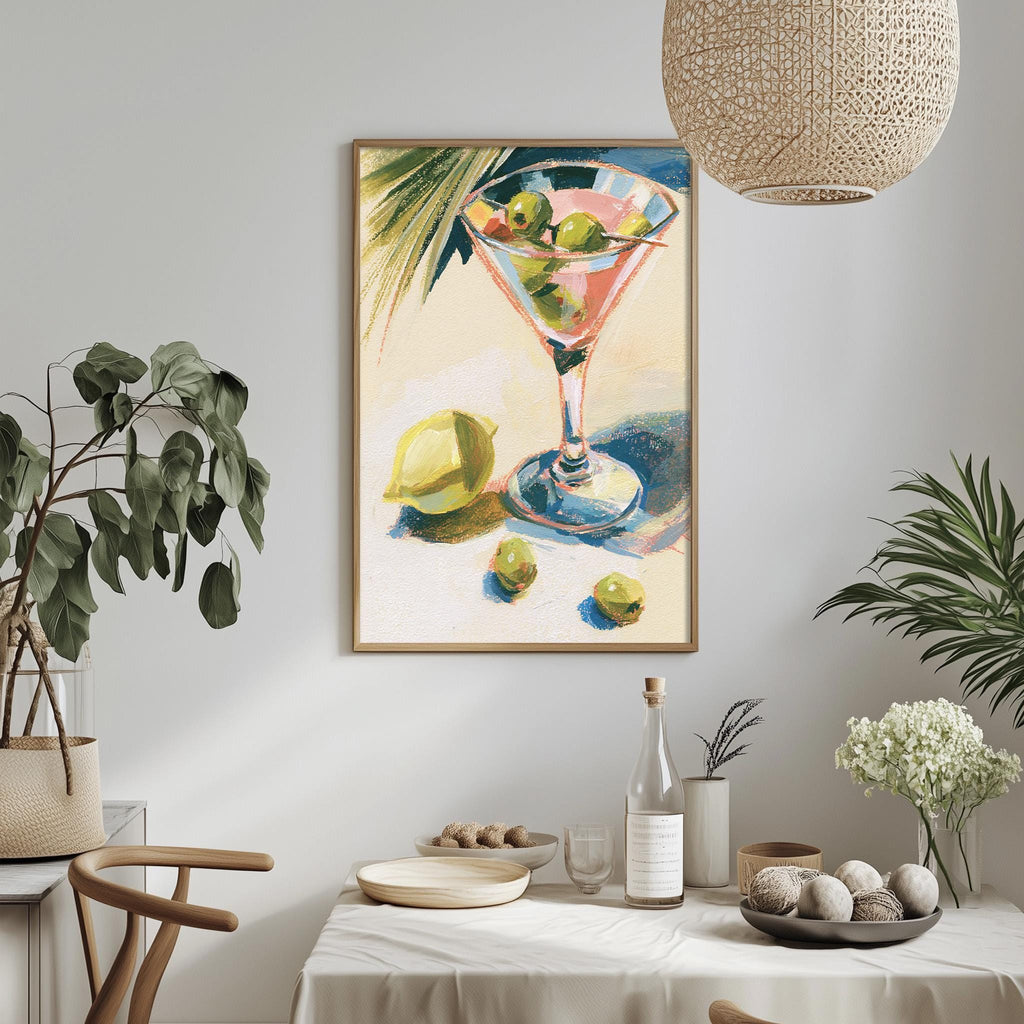 a framed painting of a martini glass with a lemon and olives, hanging on a wall above a table with various decorative items and plants.