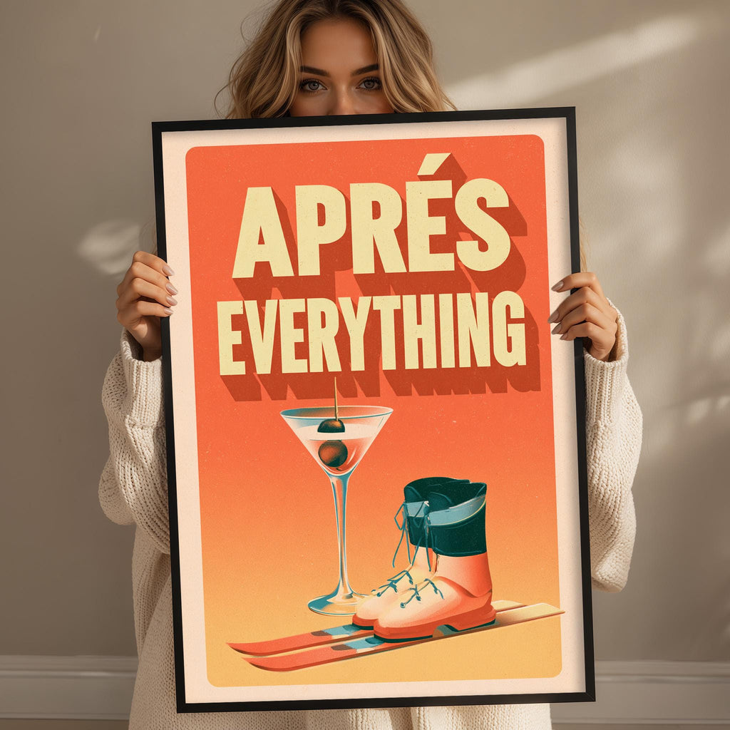 A woman holding a framed poster with an illustration of a martini glass, skis, and boots, along with the text "APRÈS EVERYTHING".