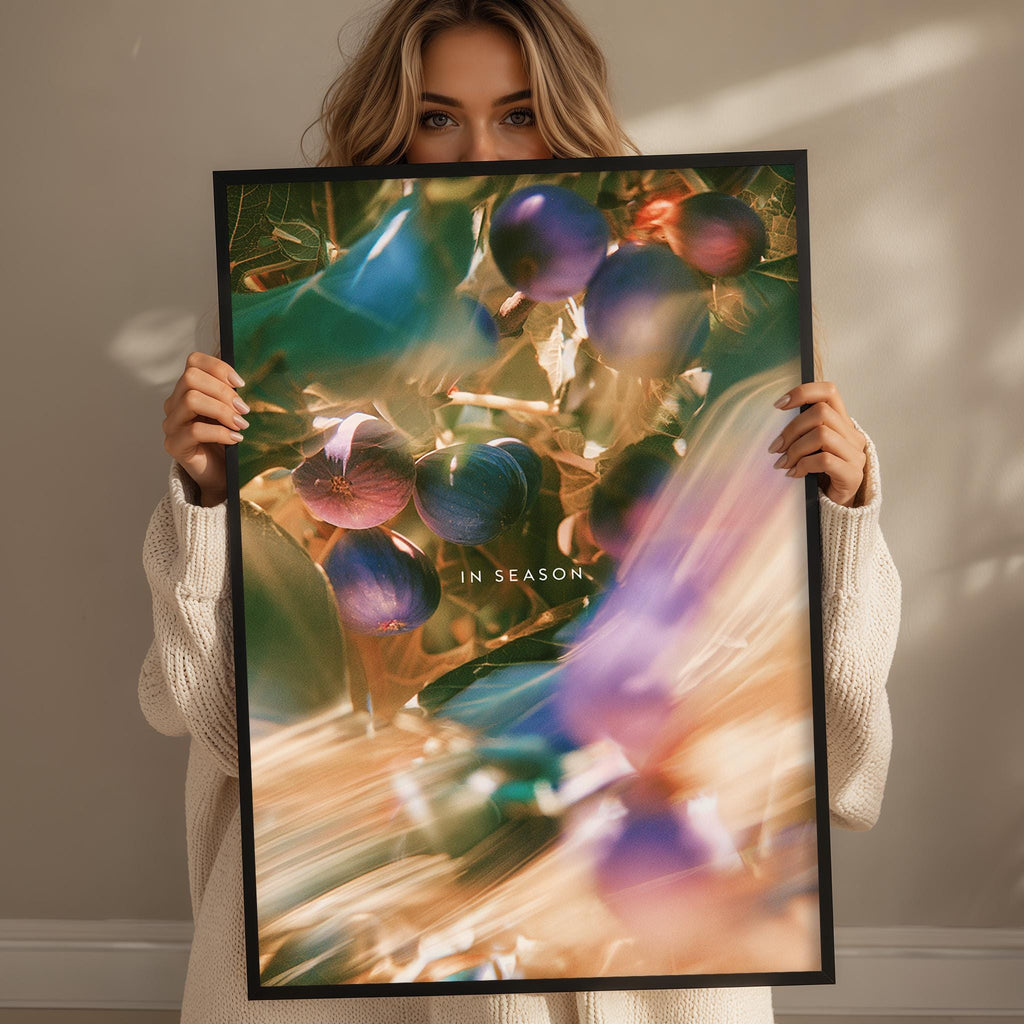 A woman holding a framed print with a colorful, abstract image of fruits and leaves.
