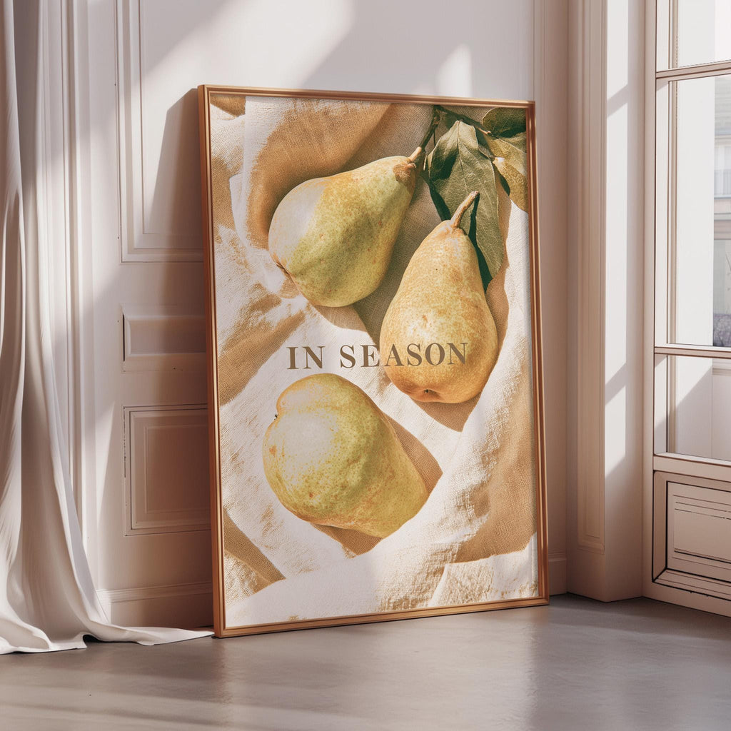 A framed poster with a close-up of three pears on a beige background, along with the text "IN SEASON" prominently displayed.