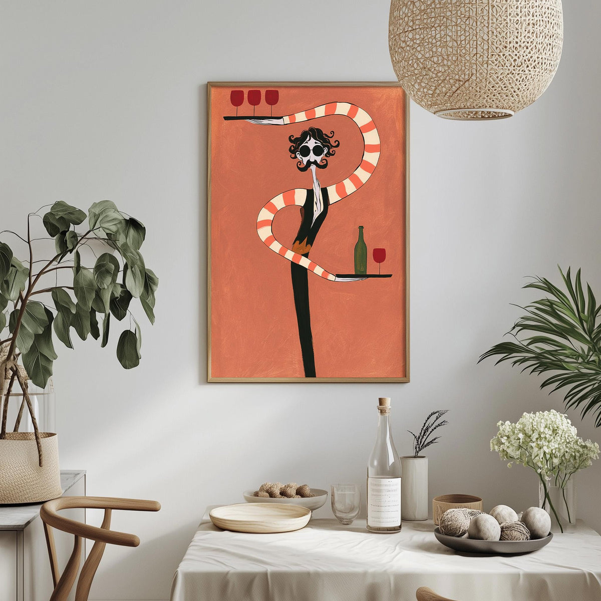 a dining table with a white tablecloth, a bowl of fruit, a bottle of wine, and a vase of flowers. Above the table, there is a framed artwork depicting a stylized figure holding a wine glass and a bottle of wine.