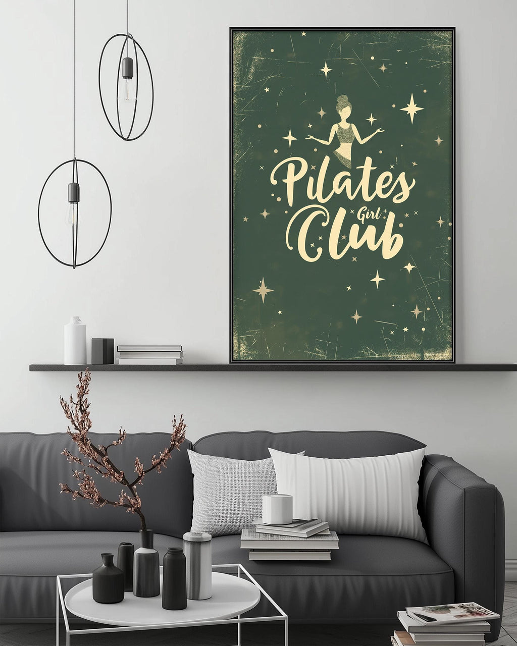 a living room with a gray couch, a coffee table, and a framed poster of the Pilates Girl Club on the wall above the couch.