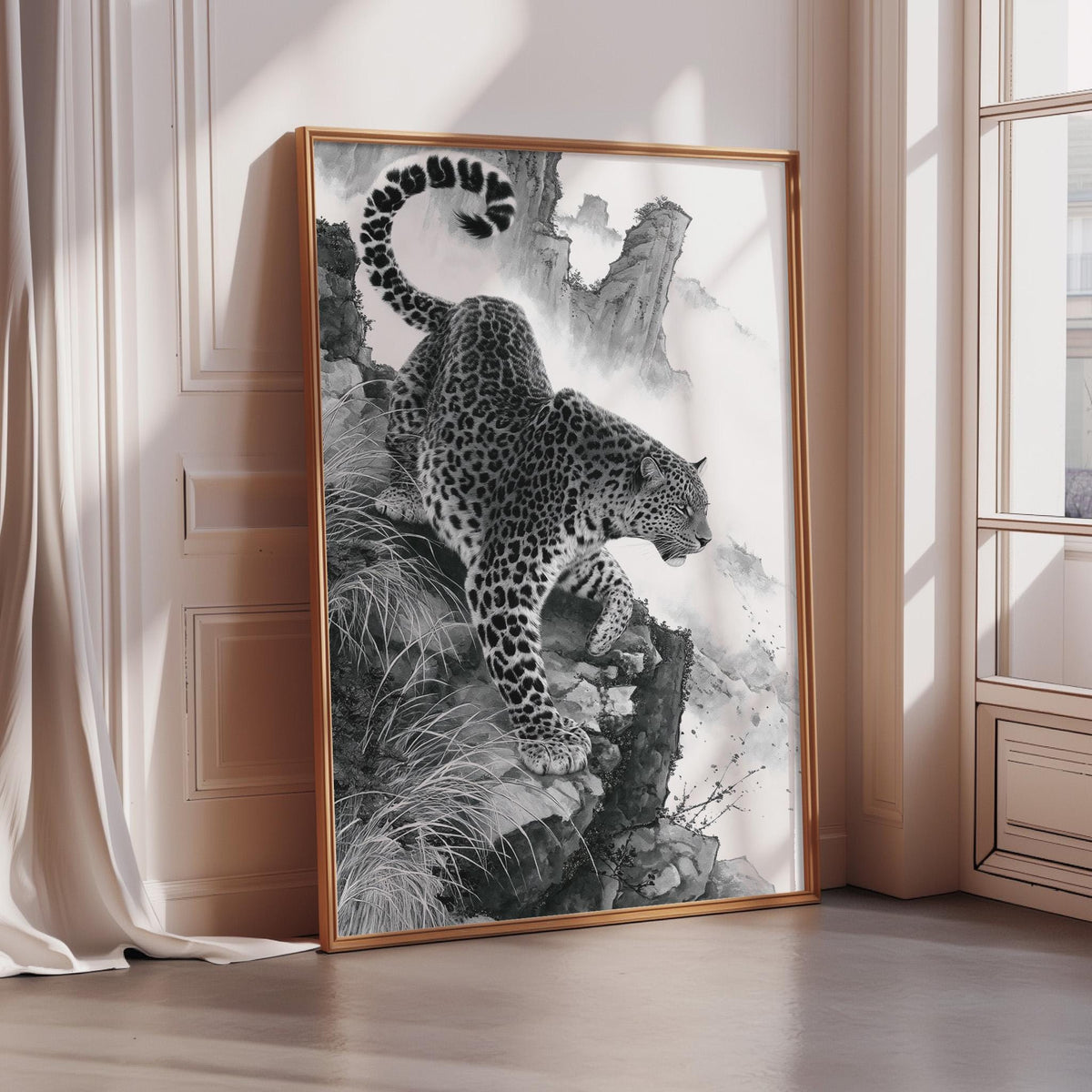 A framed black and white image of a leopard standing on a rocky cliff, with its tail curled around its body.