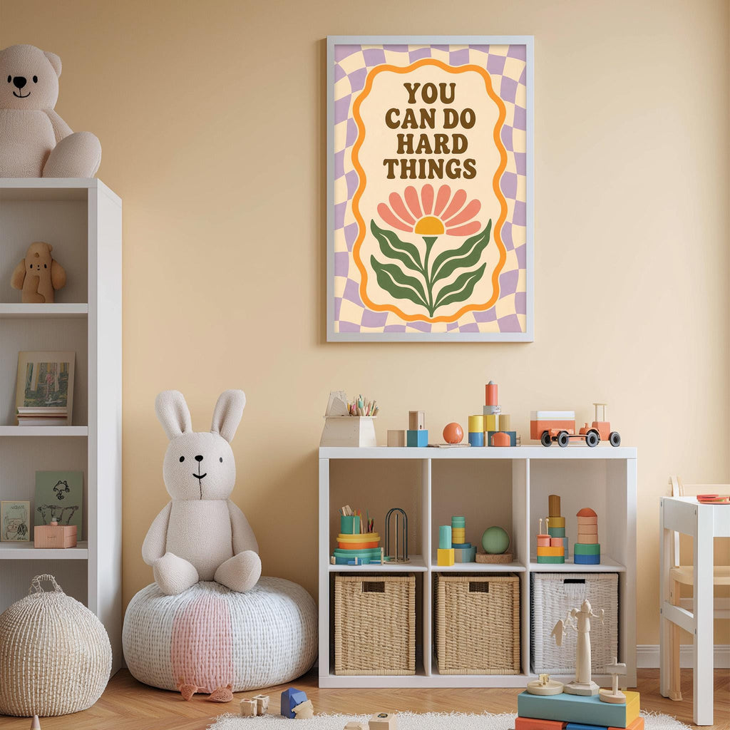 A child's bedroom with a white bookshelf, a stuffed rabbit, and a colorful poster on the wall. The poster has the text "YOU CAN DO HARD THINGS" and features a flower design.