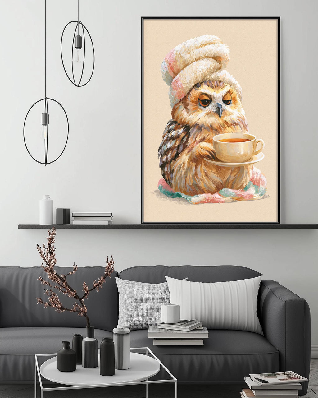 a cozy living room with a gray couch, a coffee table, and a large framed picture of an owl wearing a hat and holding a cup of tea.