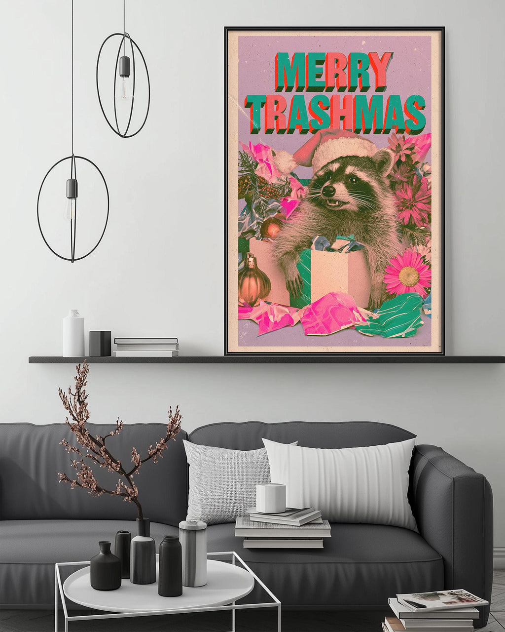 a large framed poster with a raccoon wearing a Santa hat and surrounded by Christmas decorations, including a gift box and flowers, on a wall above a gray couch and a coffee table.