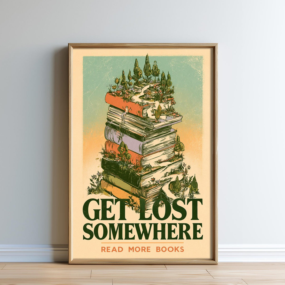 The image is a framed poster with a stack of books on top of it, surrounded by a forest scene. The poster has the text "GET LOST SOMEWHERE READ MORE BOOKS" written on it.