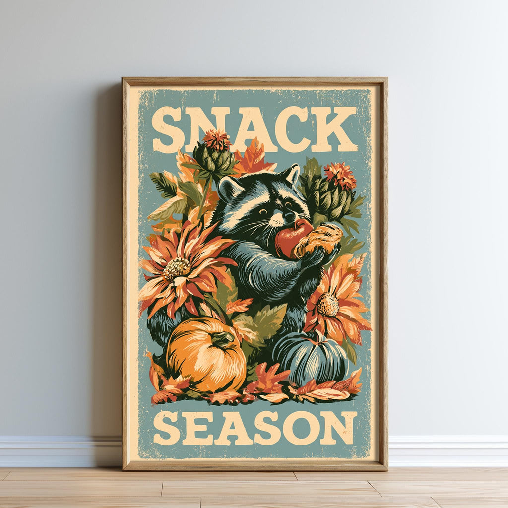 The image is a framed poster featuring a raccoon surrounded by autumn-themed elements such as flowers, pumpkins, and leaves. The text "SNACK SEASON" is prominently displayed on the poster.