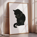 A framed black and white illustration of a cat sitting on a white surface.
