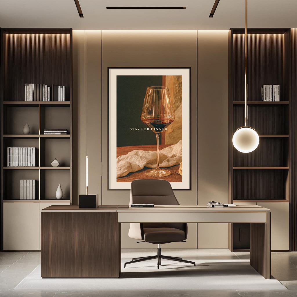 a modern and stylish office space with a large framed poster on the wall that reads "STAY FOR DINNER". The office has a wooden desk, a comfortable chair, and a bookshelf filled with books and decorative items. The overall design and decor create a professional and inviting atmosphere.