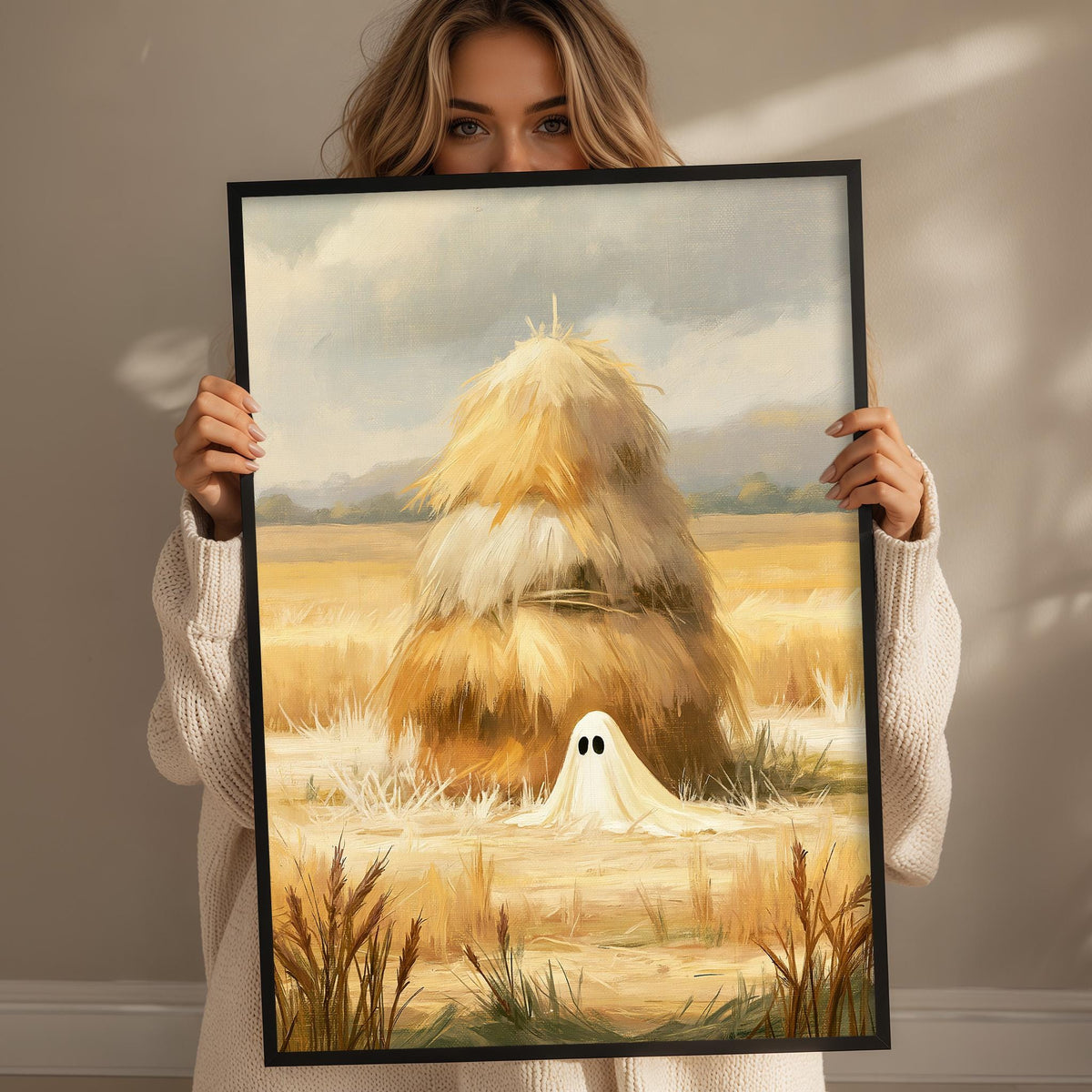 A woman holds up a framed painting depicting a ghost in a field with hay bales.