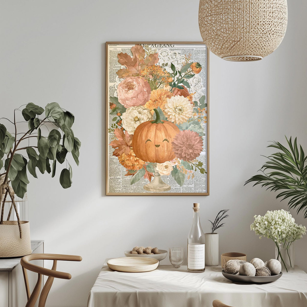 a dining table with a white tablecloth, a vase of flowers, a bottle, and a bowl of fruit. Above the table, there is a framed picture of a pumpkin with a smiling face, surrounded by autumn-themed flowers.