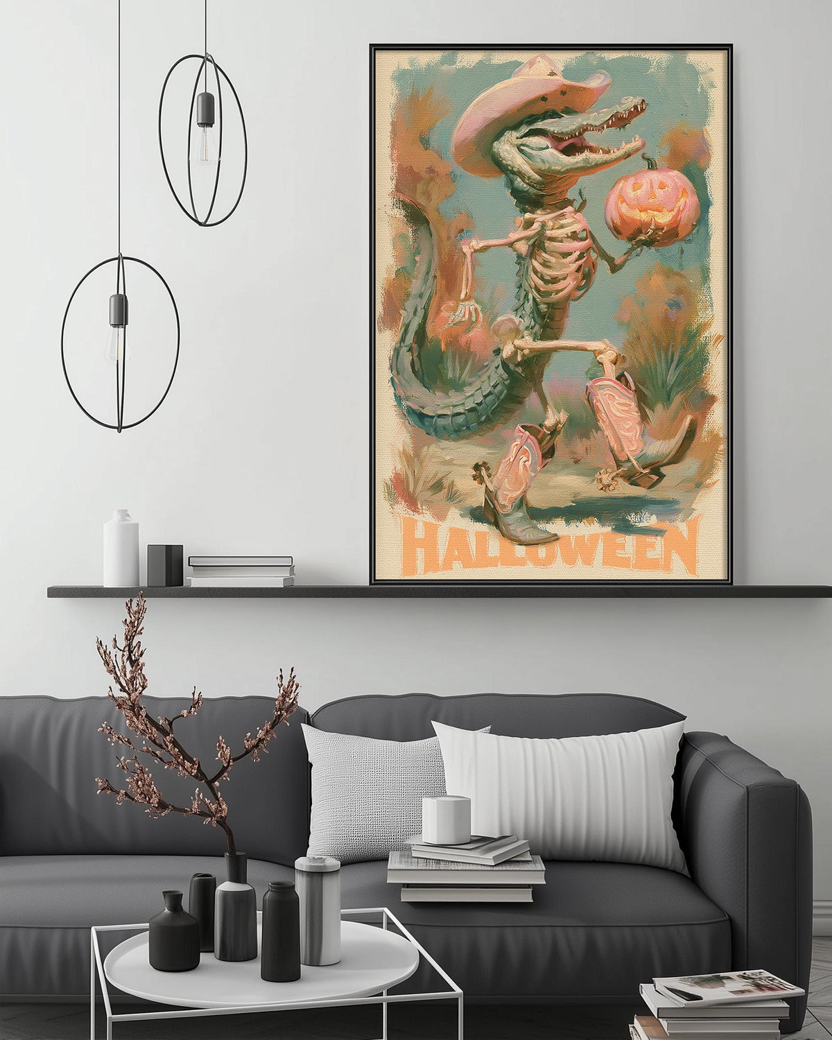 a large framed poster of a skeleton clown holding a pumpkin, hanging on a wall above a gray couch with a coffee table in front of it.