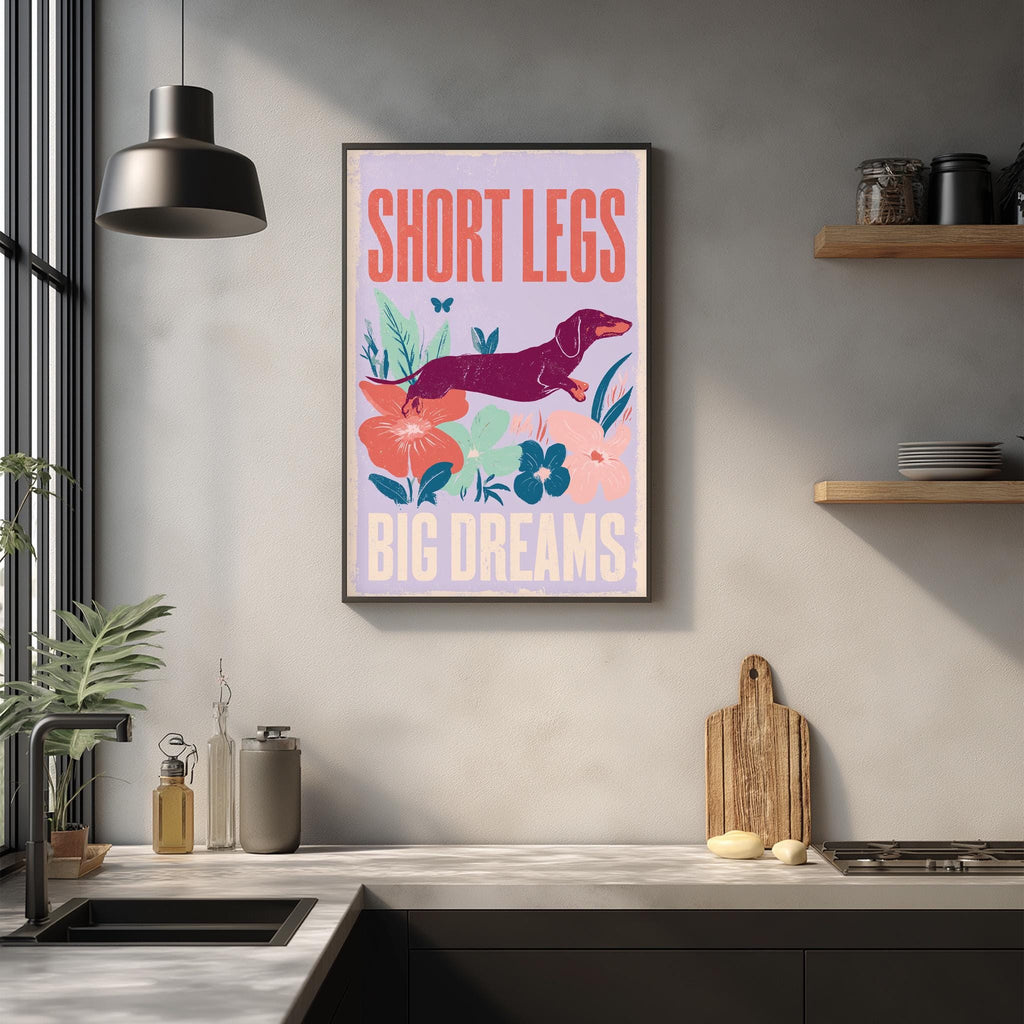 a kitchen counter with various items such as a cutting board, a soap dispenser, and a plant. Above the counter, there is a framed poster with the text "SHORT LEGS BIG DREAMS" and an illustration of a dachshund.
