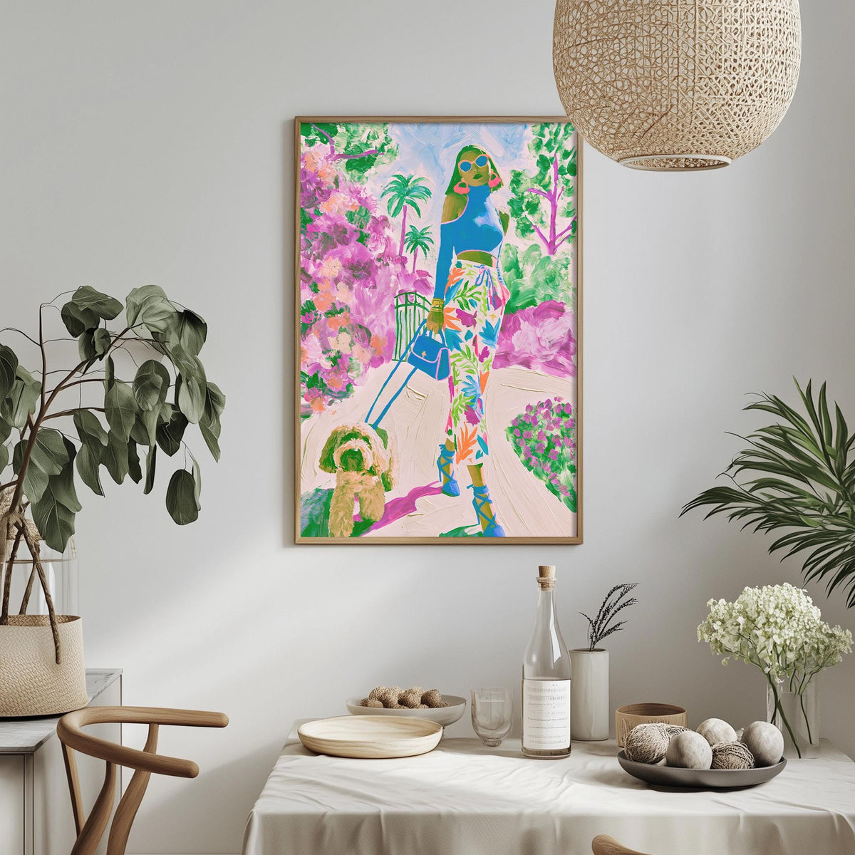 a vibrant and colorful painting of a woman walking with a dog in a tropical garden setting, hanging on a wall above a dining table with various decorative items and plants.
