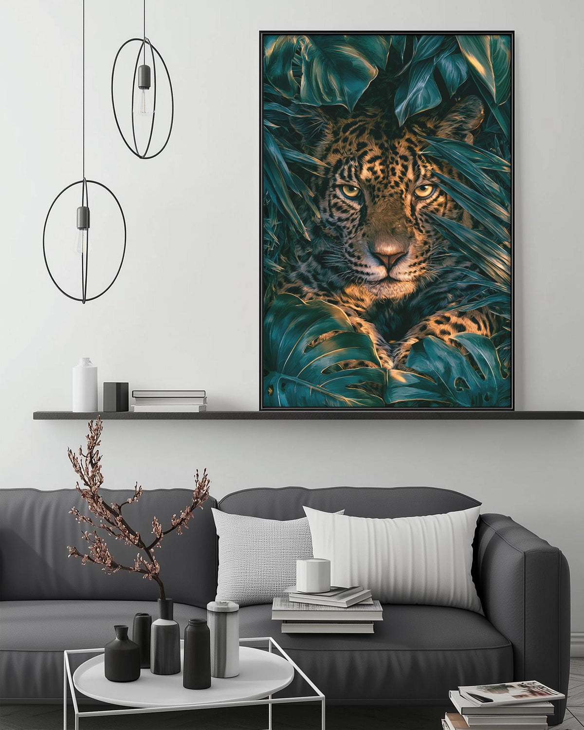a large framed picture of a leopard resting on a bed of green leaves, hanging on a wall above a gray couch in a living room setting.