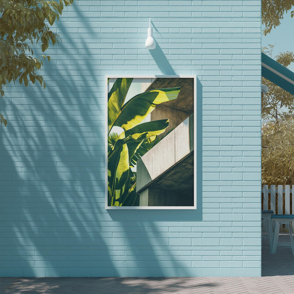 a large framed picture of a banana leaf hanging on a light blue brick wall.