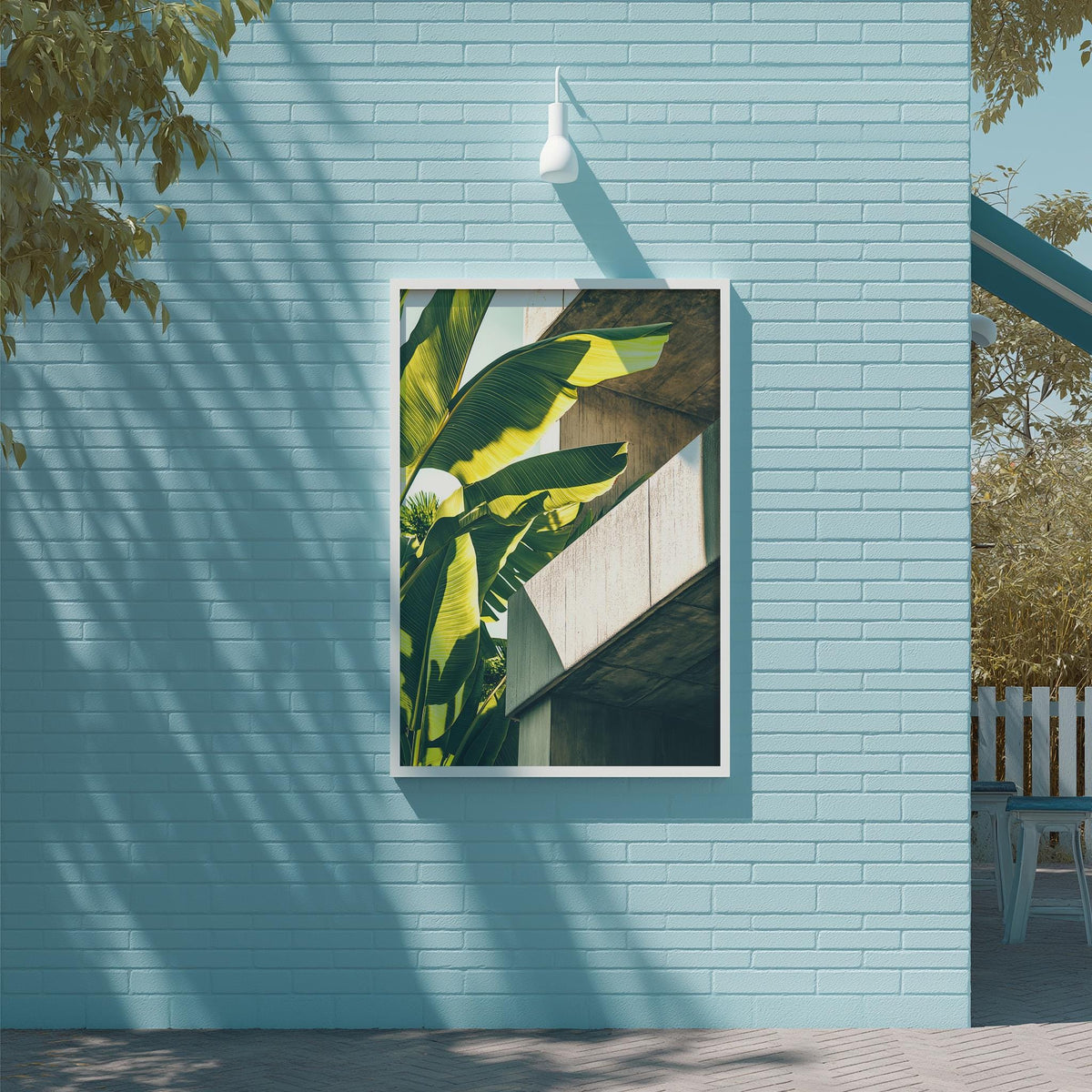 a large framed picture of a banana leaf hanging on a light blue brick wall.