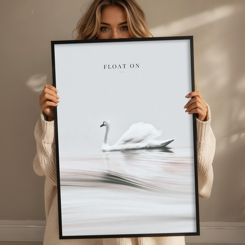 A woman holding a framed picture of a swan in a body of water.