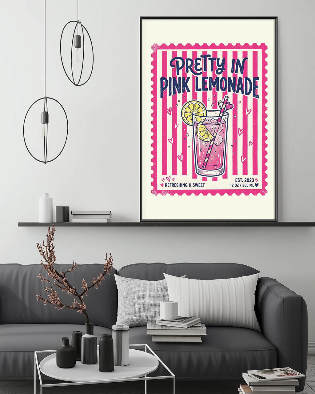 a poster of a pink lemonade drink hanging on a wall above a gray couch with a coffee table in front of it.