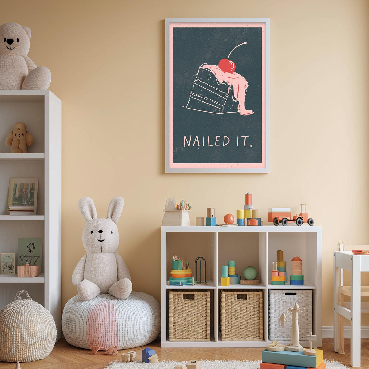 A child's bedroom with a white bookshelf, a stuffed rabbit, and a colorful toy box filled with toys. Above the bookshelf is a framed poster with a cartoon image of a cake and the text "Nailed it."