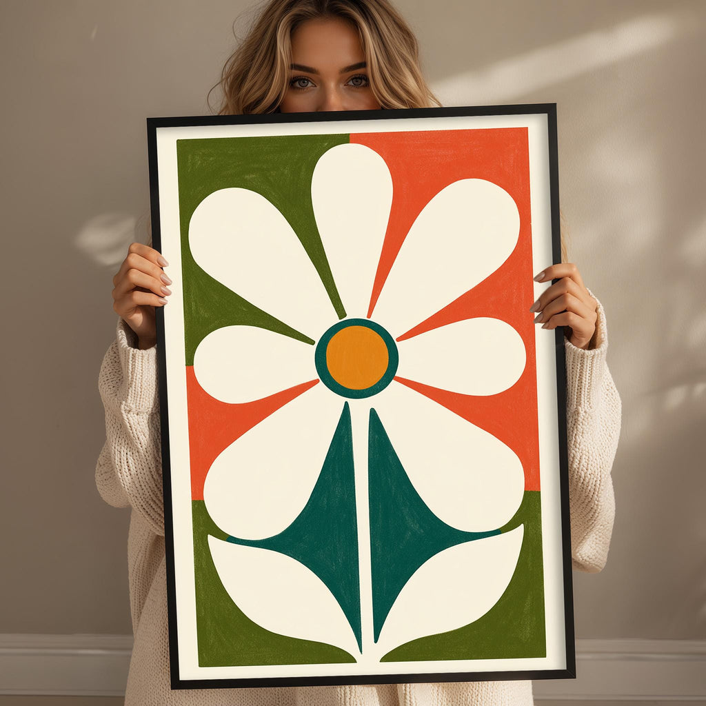 A woman is holding up a large framed print of a colorful abstract flower design.