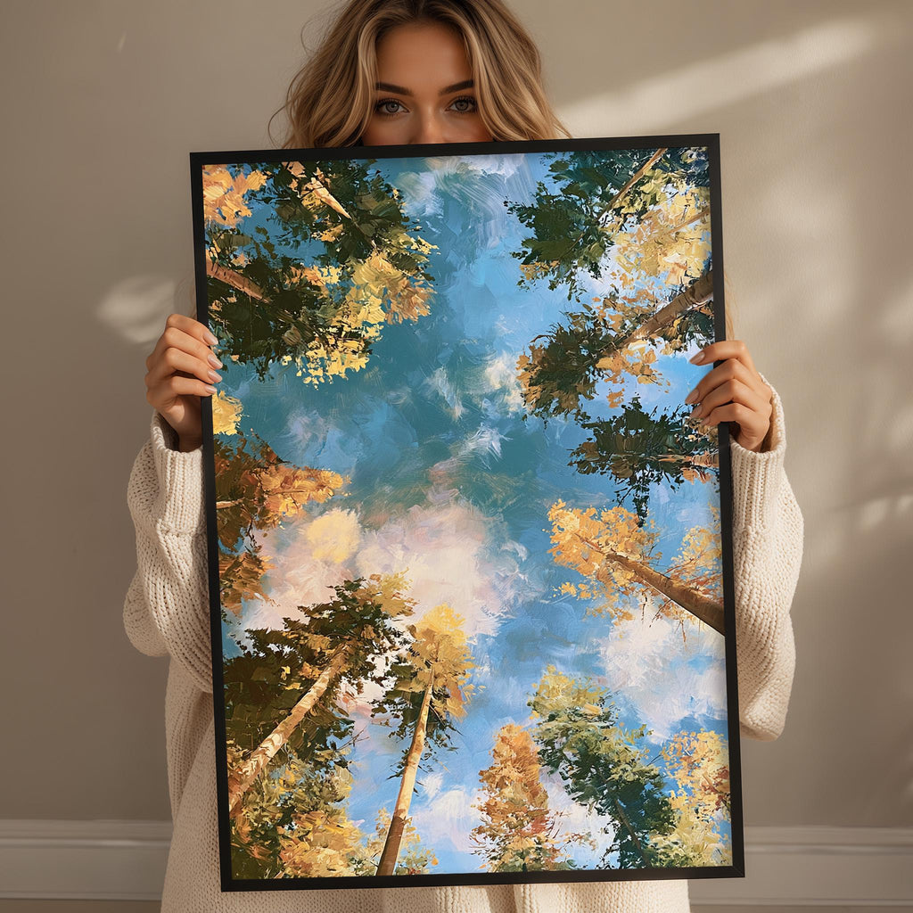 A woman holds up a framed painting of a forest scene with trees and a blue sky.