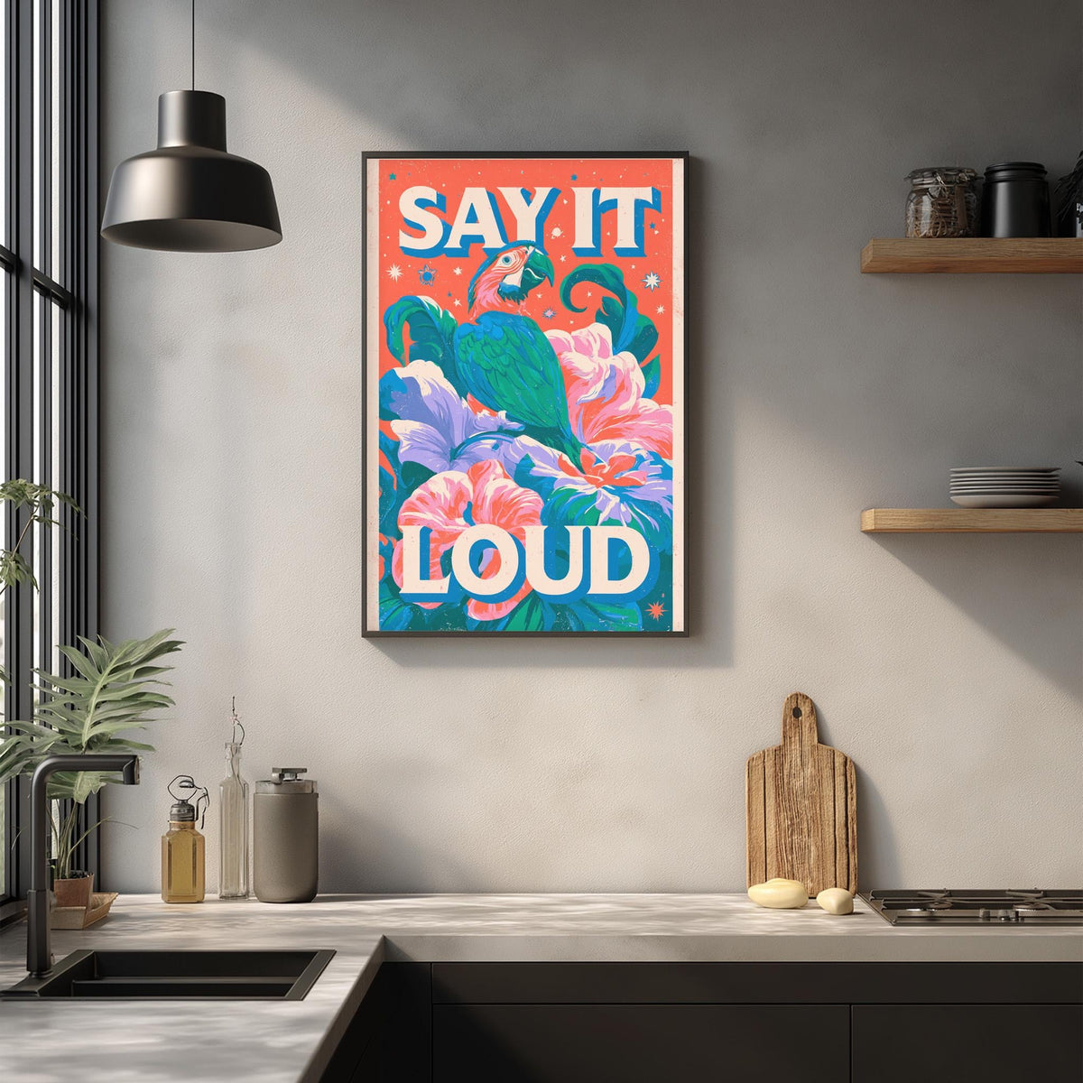 a kitchen counter with a framed poster hanging on the wall above it. The poster has a colorful design with flowers and the text "Say it loud" written in bold letters.