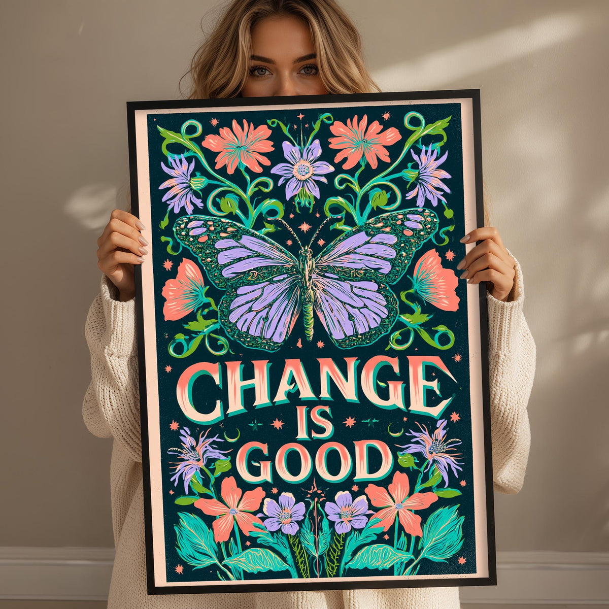 A woman holding a framed poster with a butterfly and floral designs, with the text "CHANGE IS GOOD" prominently displayed.