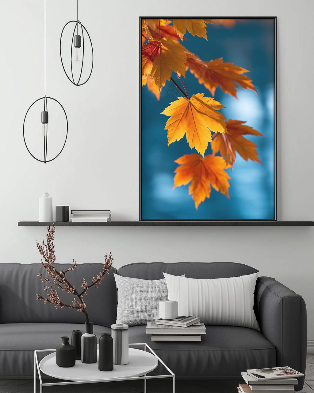a large framed picture of autumn leaves hanging on a wall above a gray couch in a living room setting.