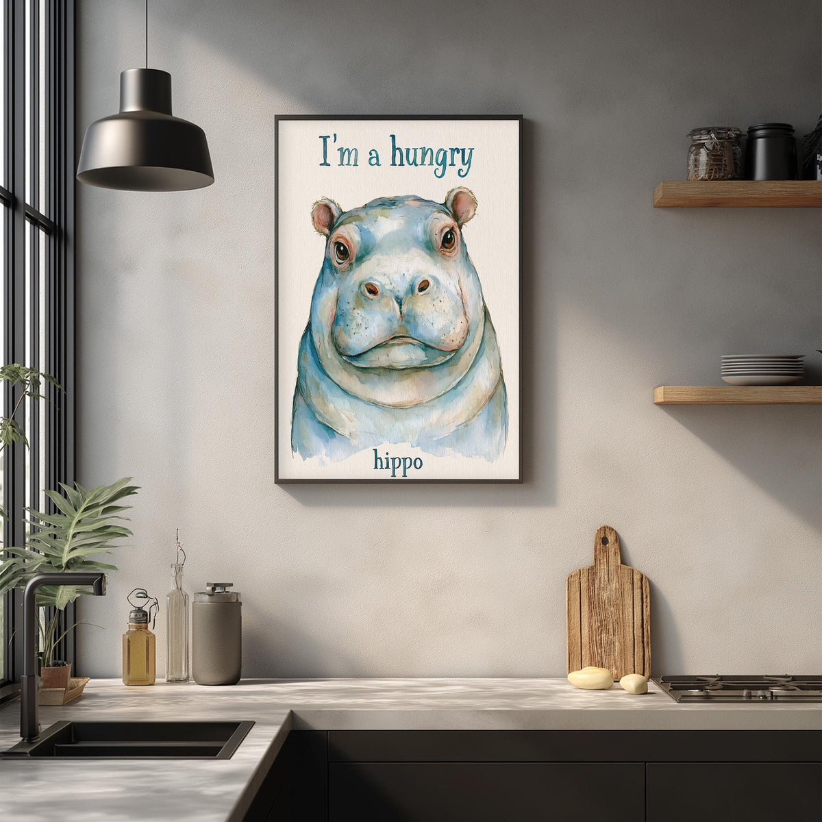 a framed watercolor painting of a hippopotamus with the text "I'm a hungry hippo" above it. The painting is hanging on a wall above a kitchen counter with various kitchen items such as a cutting board, a bottle, and a bowl.