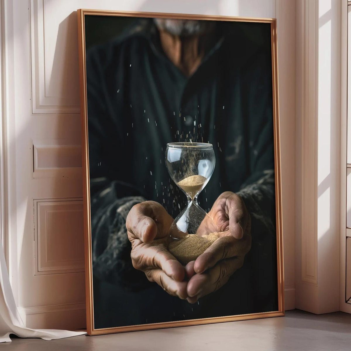 A person's hands holding a glass hourglass, with sand grains visible through the glass, against a white wall.