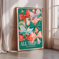 A framed poster with a colorful design featuring bows, flowers, and other festive elements, placed on a wall near a window.