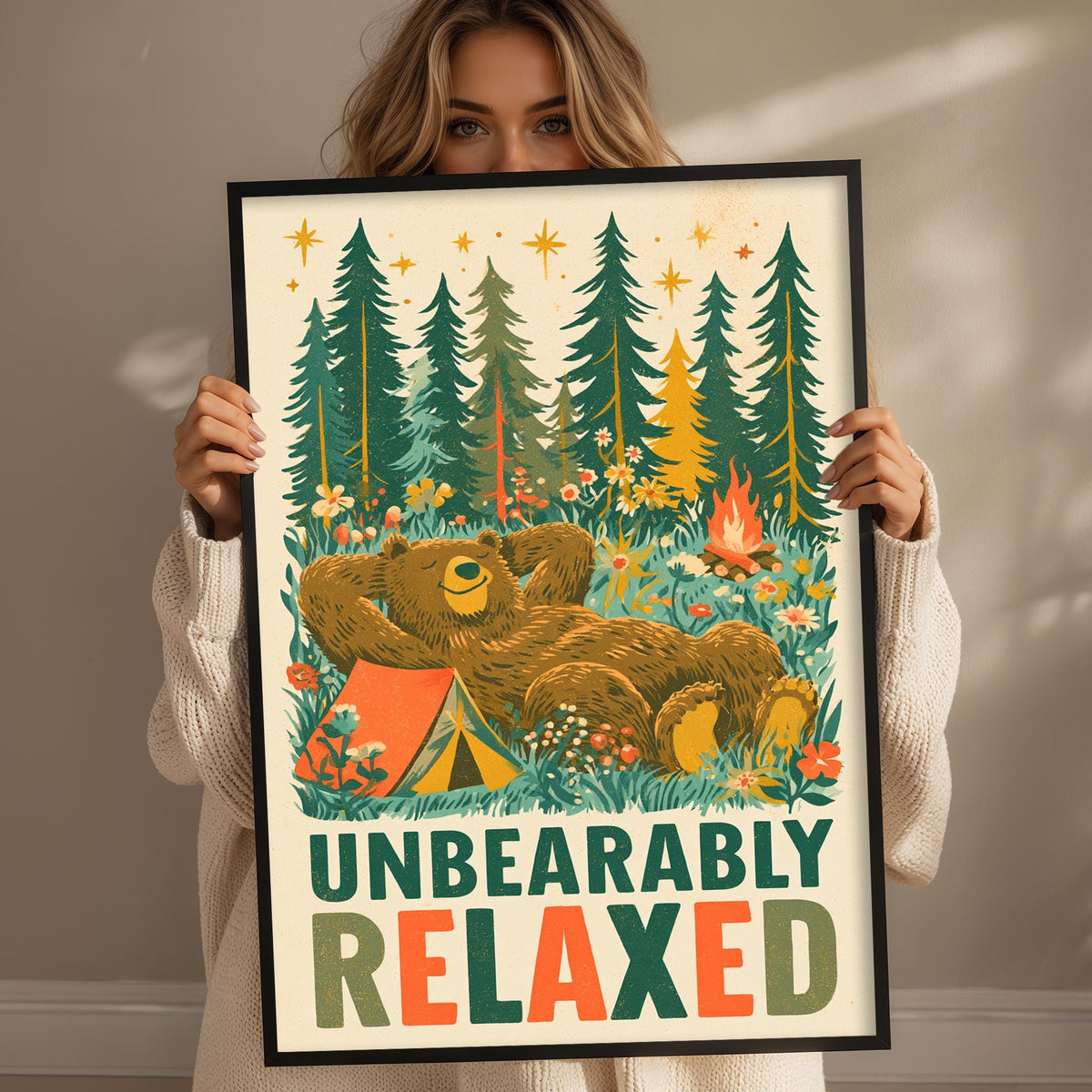 A woman holding a framed poster with a bear and camping scene on it.