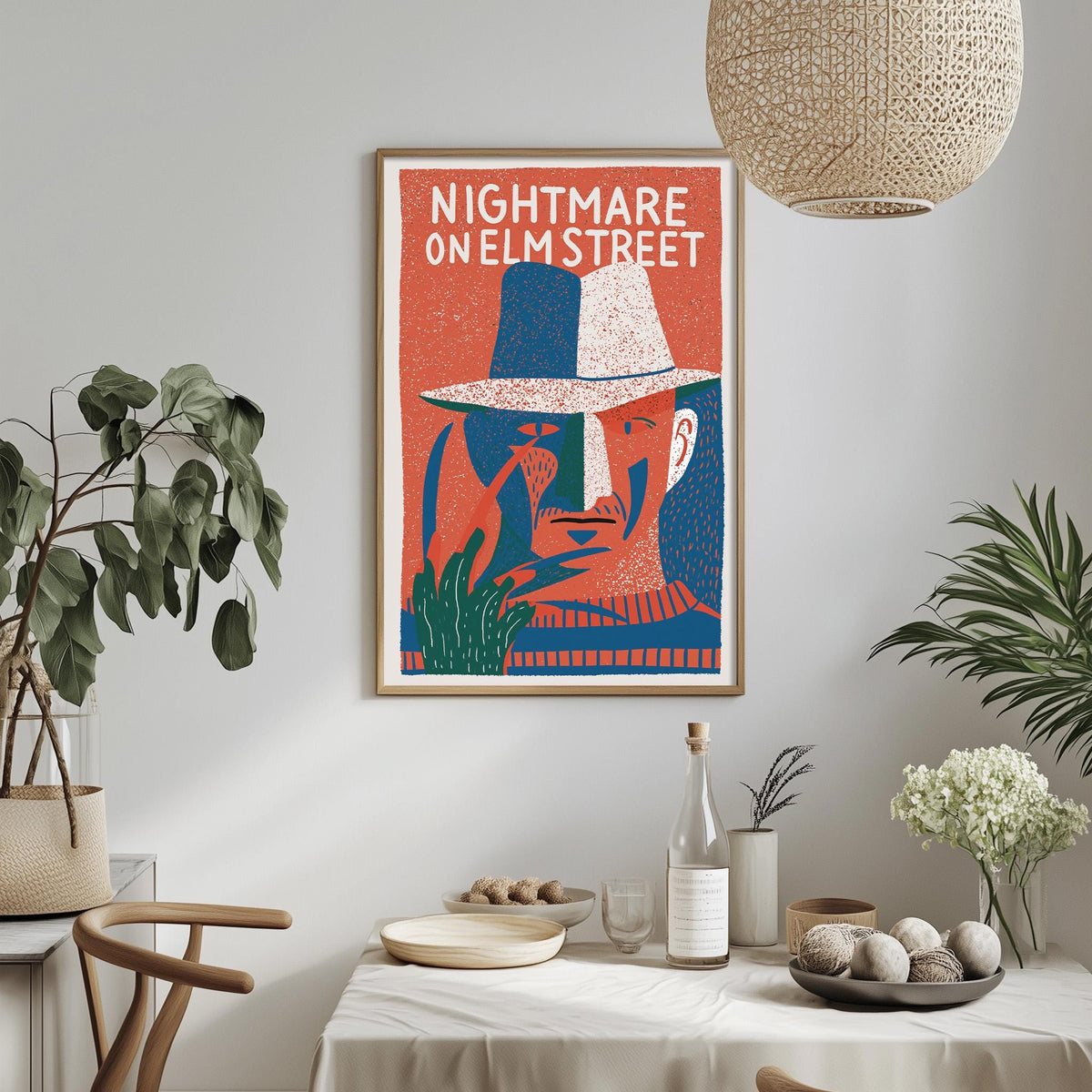 a framed poster of a man's face with a hat, hanging on a wall above a dining table with various items on it.