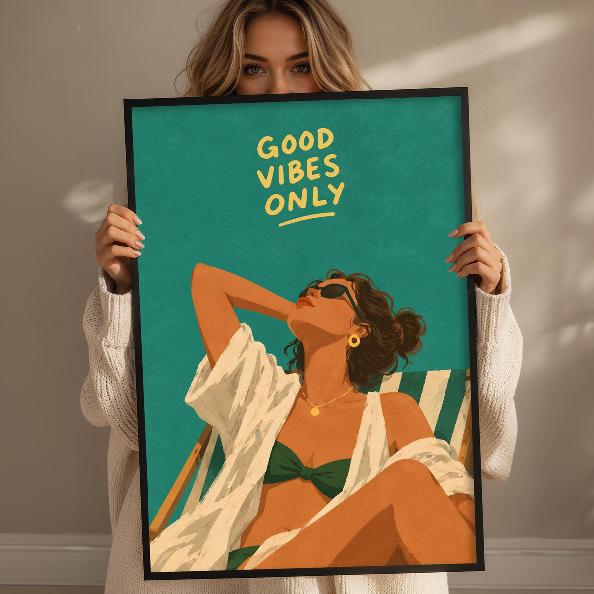 A woman holding a framed poster with a woman in a bikini and sunglasses on it.
