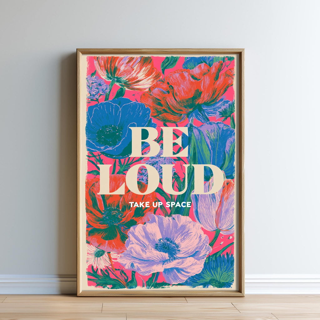 The image is a framed poster with a vibrant floral design and the text "BE LOUD TAKE UP SPACE" displayed prominently.